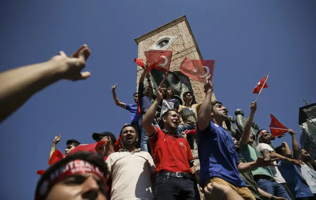 People wave Turkish flags as they stand around the Republic Monument in Taksim Square in Istanbul, Turkey, July 16, 2016