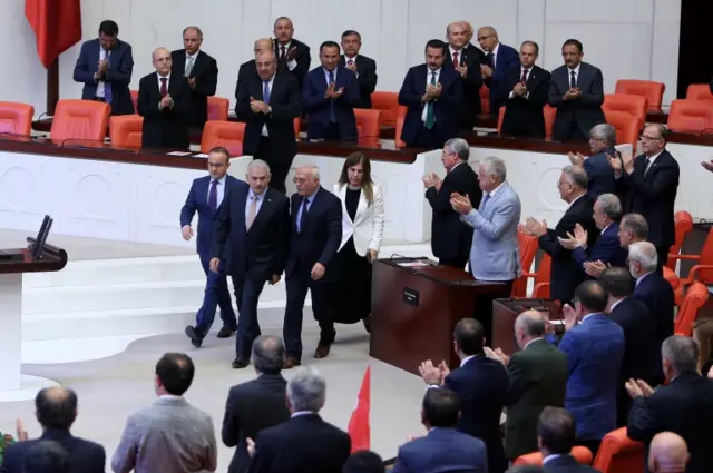 Turkish Prime Minister Binali Yildirim (C) and lawmakers attend a extraordinary assembly at Turkish Parliament