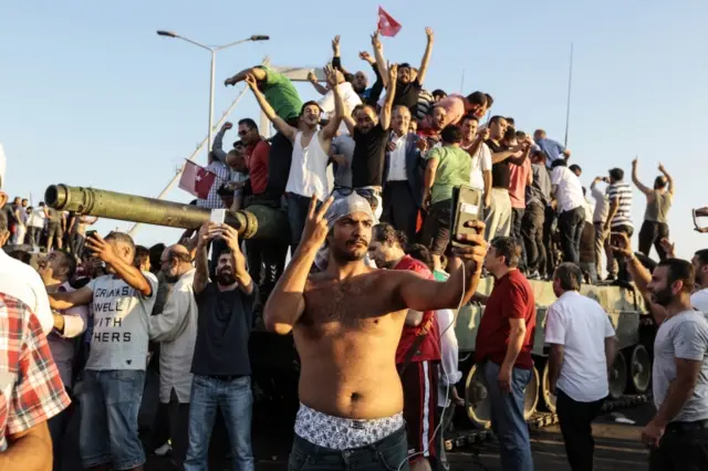 Supporters of Turkish President Recep Tayyip Erdogan wave flags as they capture anTurkish Army Armoured Personnel Carrier after soldiers involved in the coup surrendered on Bosphorus bridge