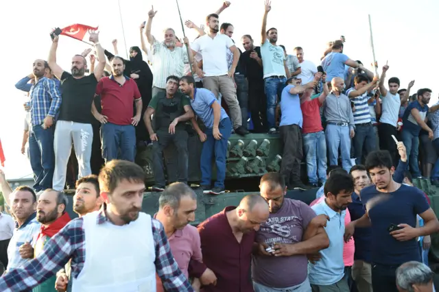 People react after they take over a military position on the Bosphorus bridge in Istanbul