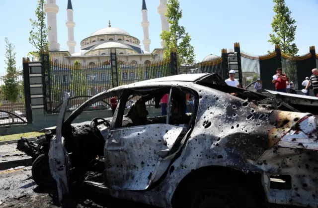 People look at destroyed cars outside the presidential palace in Ankara