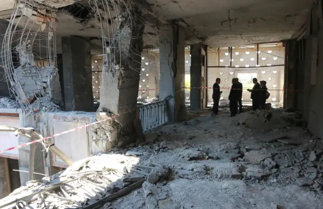 People stand in the middle of the rubble after the Grand National Assembly of Turkey was bombed