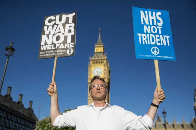 Man holding up placards outside Parliament opposing Trident renewal