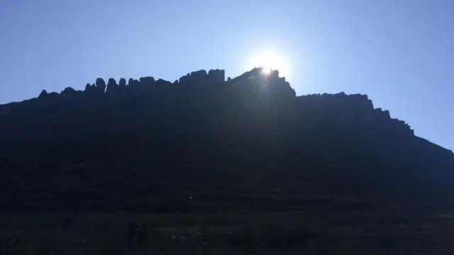 Sun peeking over a rocky hill