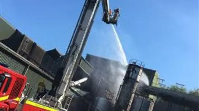 Firefighters platform firing water at industrial building