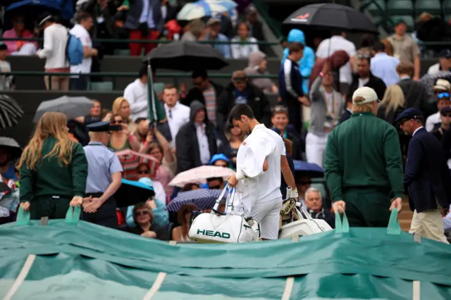 Novak Djokovic leaves Court One for a rain delay