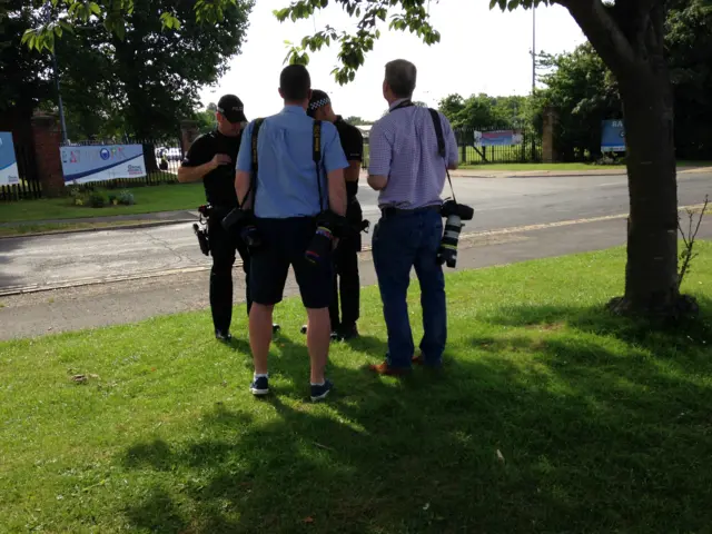 Two police officers and two members of the media being checked for weapons