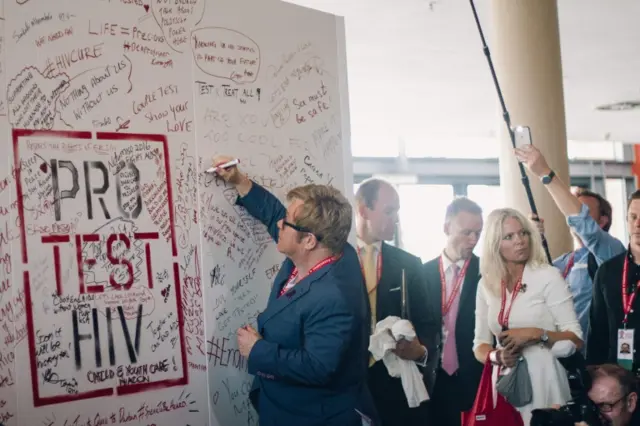 British singer Elton John signs the protest wall during the International Aids Conference at the international convention centre in Durban on July 21, 2016.