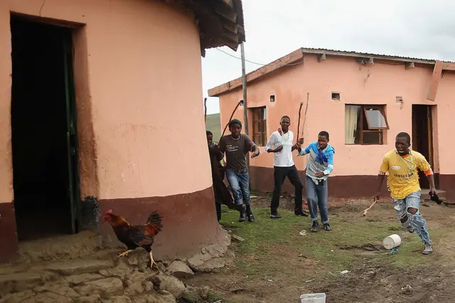 Youths chase a chicken on December 13, 2013 in Qunu, South Africa