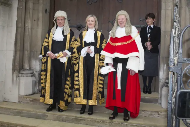 Lord Neuberger in black and gold robes and wig, Ms truss in black and gold, and Lord Dyson in red and gold with a wig