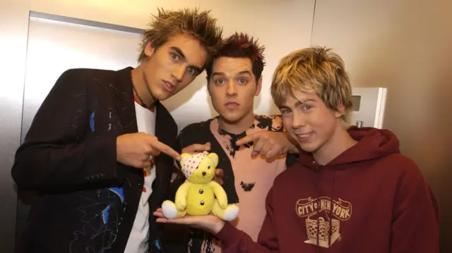 Charlie, Matt and James from Busted hold Pudsey bear