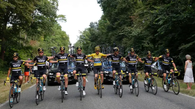 Team Sky link arms and ride down the road