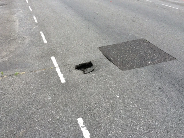 The hole in the road, to the right of white lines