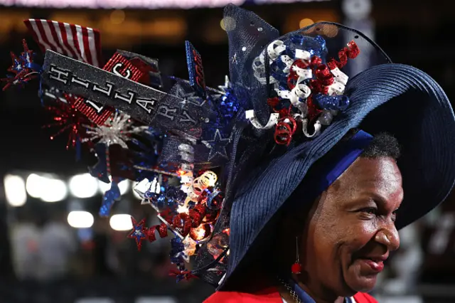 A woman wears a large Hillary Clinton hat