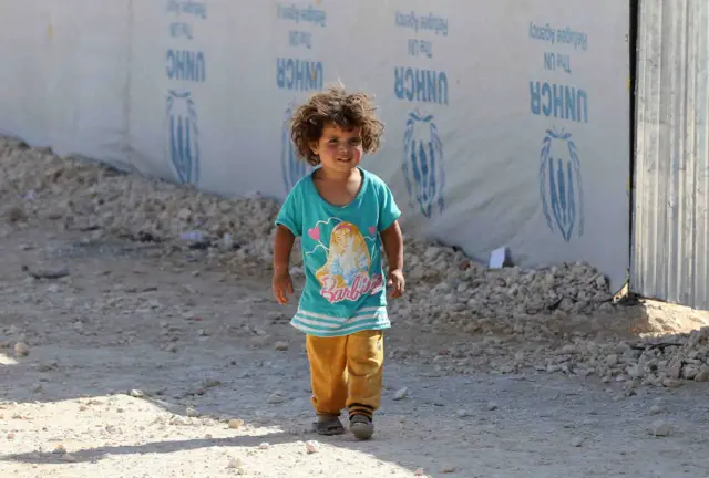 A Syrian refugee child walking at a refugee camp