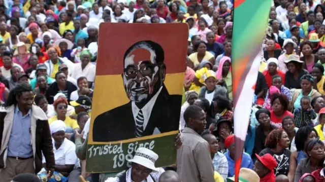 Zimbabweans holding up a poster of President Robert Mugabe