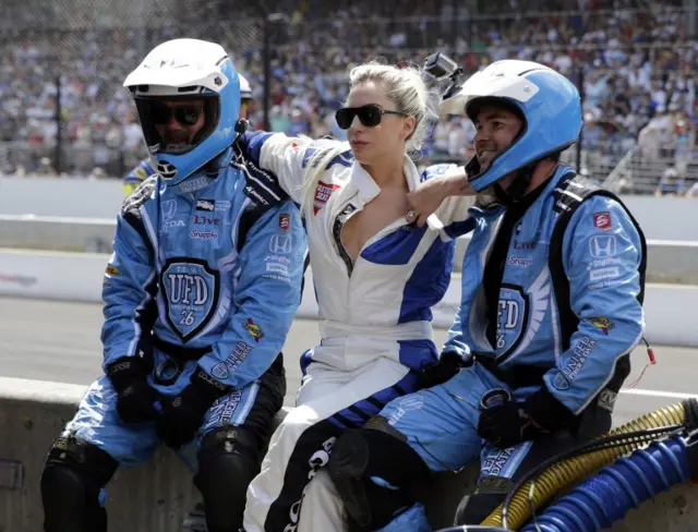 Lady Gaga poses with members of the Carlos Munoz pit crew during the 100th Indianapolis 500 auto race