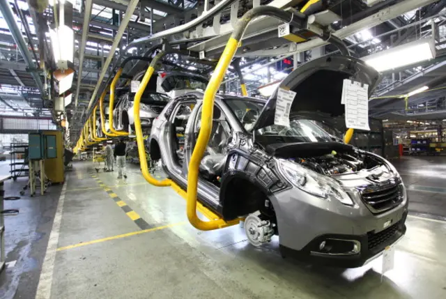 Peugeot 208 cars sit on a conveyor at the PSA Peugeot Citroen assembly plant in Mulhouse