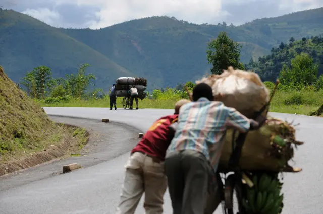 Burundian men pushing loaded cyclists