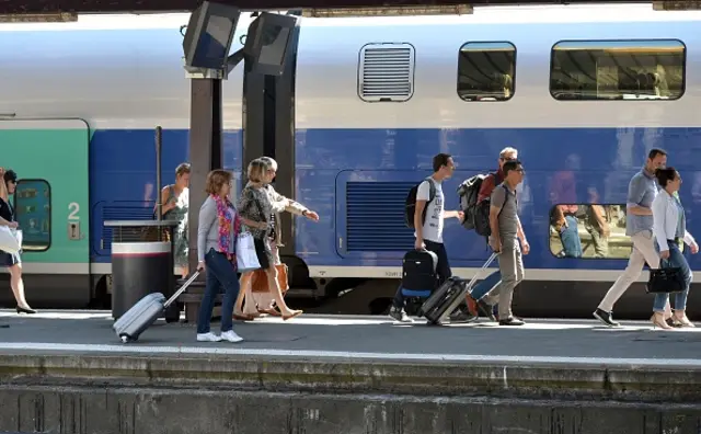 Train passengers walk along a platform after arriving at the railway station of Toulouse