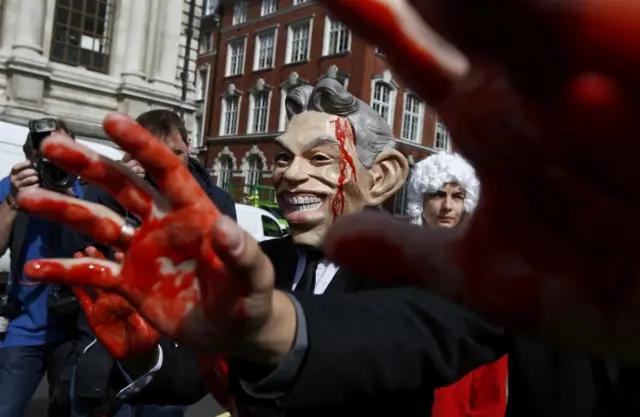 A demonstrator wears a Tony Blair mask and covers his hands in fake blood