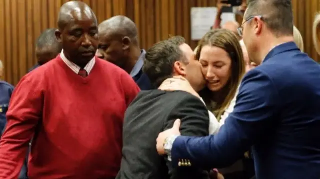 Oscar Pistorius (C) holds his sister Aimee Pistorius as he leaves the High Court in Pretoria, on July 6, 2016 after beeing sentenced to six years in jail for murdering his girlfriend Reeva Steenkamp