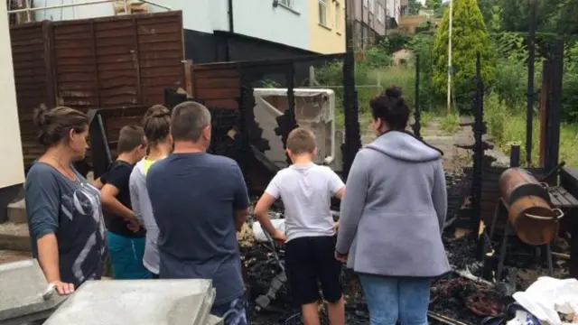 Family outside burnt out shed