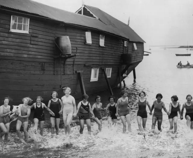 Young girls on holiday in Suffolk splash around outside their accommodation the houseboat Ionia