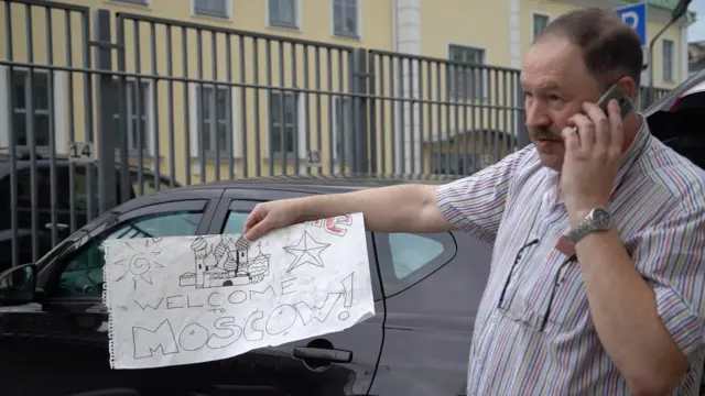 A cab driver holing a welcome to Russia sign