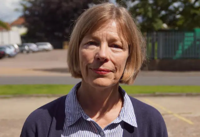 Susan Carne in dark blue cardigan and blue striped blouse