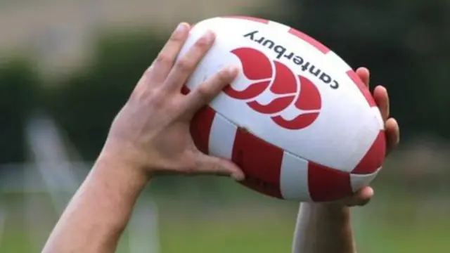 Hands holding a rugby ball