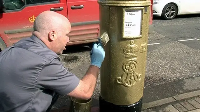 Man painting post box gold in 2012