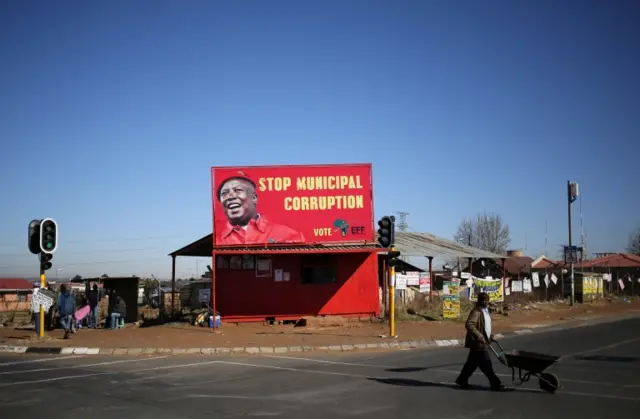 man pushes a wheelbarrow past a billboard of the Economic Freedom Fighters (EFF), which is led by Julius Malema, President Jacob Zuma"s one-time protege and a former ANC youth leader, in Soweto, South Africa, August 5,2016