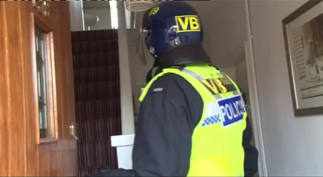 Police officer stands in hallway of a house