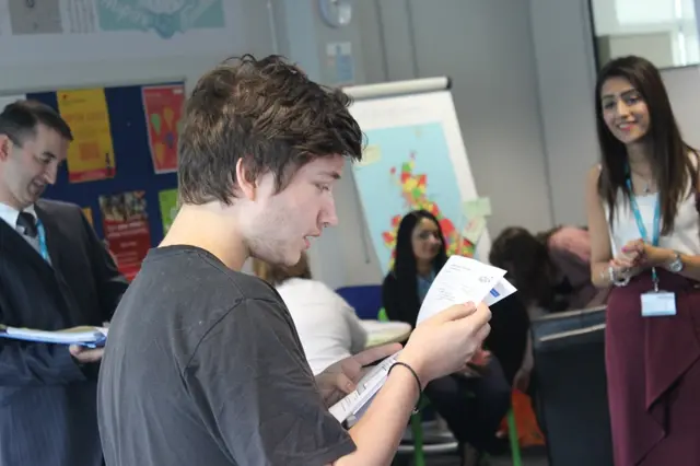 Teachers look on as student reads A-level results