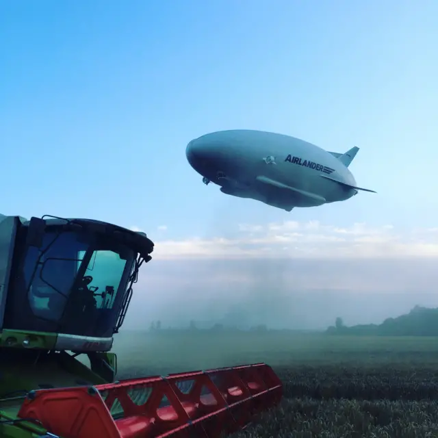 Airlander flies over combine harvester in field