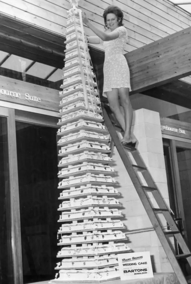 Bride Kathy Aylwin needs a stepladder to get to the top of her cake