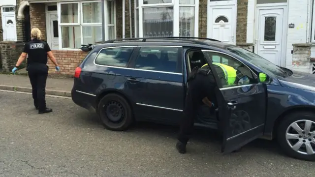 Police officers search a car