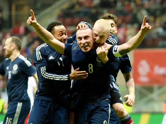 Scott Brown is mobbed after scoring against Poland in Warsaw