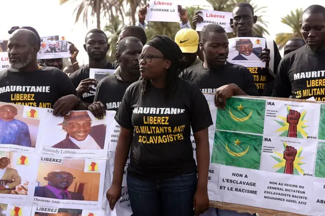 Anti slavery militants hold a banner which translates as 'No to slavery and racism, no to the regime of the general dictator slavery racist Mouhamed Abdel Aziz' demonstrate on August 3, 2016 in Dakar against the imprisonement of fellow activists in Mauritania