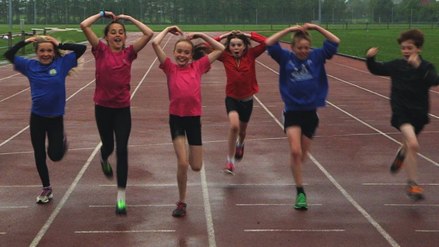 Kids running on an athletics track doing the 'Mobot'