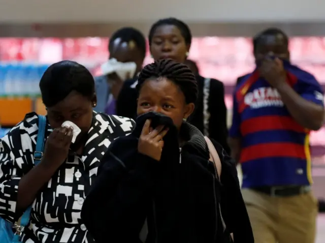 Locals cover their faces during a protest by opposition youths who were demonstrating against alleged brutality by security agents in the capital Harare, Zimbabwe August 24, 2016.