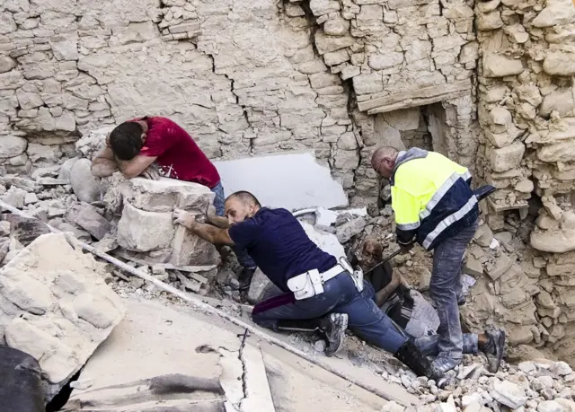 A man cries as another injured is helped in Amatrice, central Italy, where a 6.2 earthquake struck just after 3:30 a.m., Wednesday, 24 August, 2016.