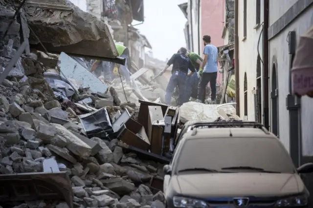 Search and rescue teams search for missing people amid the rubble of collapsed buildings in Amatrice