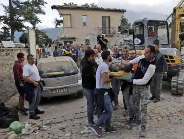 A man is carried out on a stretcher from a collapsed building in Amatrice