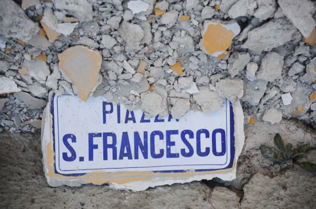 A sign showing the name of a square under rubble in the central village of Accumoli