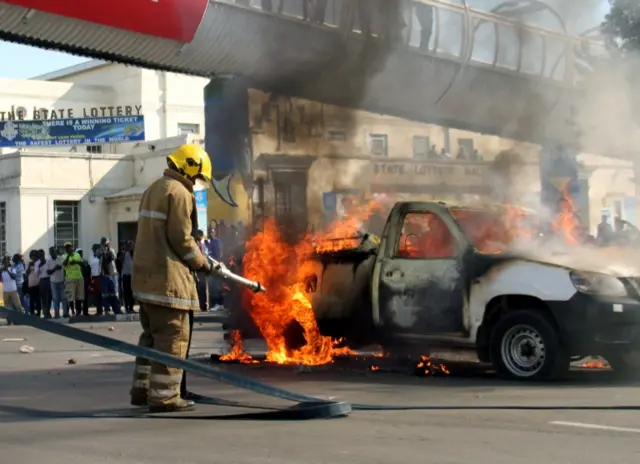 A fire fighter extingushes a pick-up truck belonging to state broadcaster, ZBC (Zimbabwe Broadcasting Corperation) during a protest by opposition youths who were demonstrating against alleged brutality by security agents in the capital Harare, Zimbabwe, August 24, 2016.