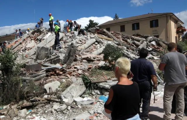 Rescuers and onlookers at a collapsed building in Amatrice