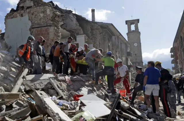 Rescuers carry a stretcher following the earthquake in Amatrice