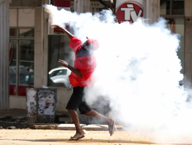 A Zimbabwean man throws back a tear gas cannister during a protest by opposition youths who were demonstrating against alleged brutality by security agents in the capital Harare, August 24, 2016.